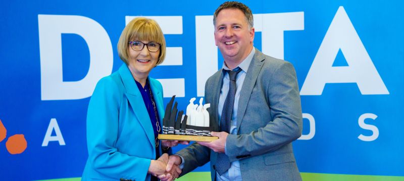 Image of a smiling Thomas Broderick, Sports, Leisure & Childhood Studies, MTU receiving his departments DELTA Award from Prof Maggie Cusack, President of MTU
